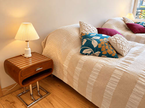 Chambre douillette à la Maison Crone Castillon avec literie crème, coussins décoratifs, table de nuit en bois et lampe chaleureuse
