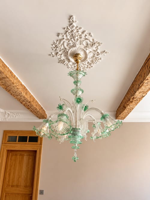 Lustre en cristal orné aux accents verts suspendu à une rosace décorée dans la Chambre Nordique de Maison Crone