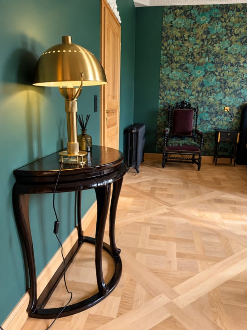Chambre Émeraude à la Maison Crone, avec lampe en laiton, console noire et motifs floraux turquoise