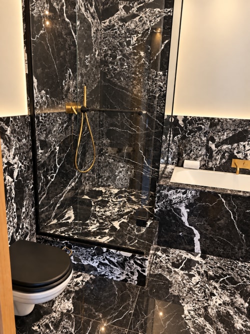 Salle de bain de luxe aux murs en marbre noir veiné de blanc, robinetterie dorée, douche vitrée - Maison Crone B&B