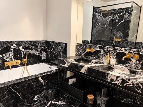Salle de bains en marbre noir luxueux à la Maison Crone avec robinetterie en laiton et double vasque