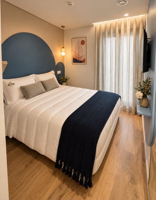 Quarto moderno da House Park Esposende com cabeceira azul, roupa de cama branca, cortinas com vista para rio e piso em madeira