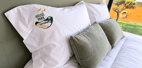 Cama do House Park Esposende com almofadas brancas e almofadões cinzentos, quarto com vista para o rio em casa de hóspedes portuguesa