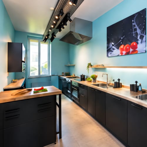 Cuisine moderne au gîte Un Air De Famille à Vittel : murs turquoise, mobilier noir et plan de travail bois