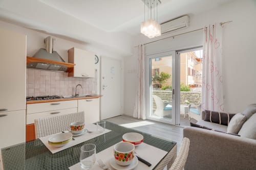 Modern studio kitchen and living area at Short Let's Olbia with dining table, sofa, and patio access