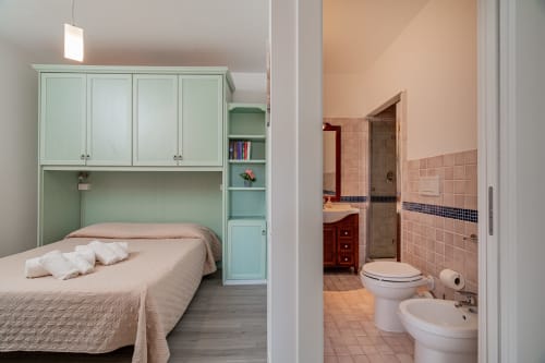 Bedroom with mint green storage unit and en-suite bathroom at Short Let's Olbia hotel in Olbia, Italy