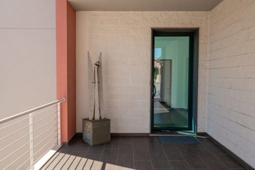 Modern entryway at Short Let's Olbia with tiled floors, coral accent wall, metal railing, and glass door entrance