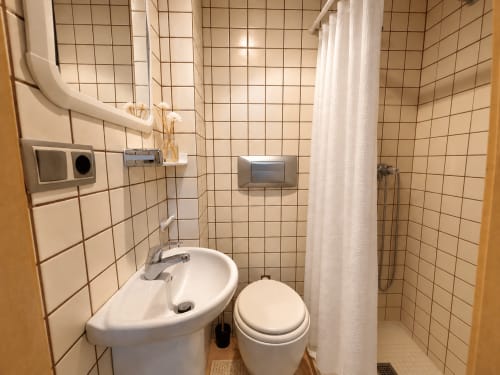 Baño compacto en apartamento de Baiona con lavabo blanco, inodoro y ducha con cortina