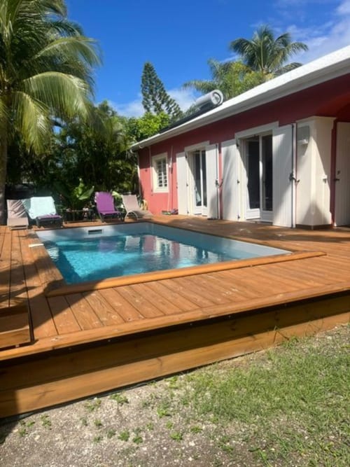 Piscine privée Villa la Désirade avec terrasse en bois, villa rouge et blanc, palmiers, bains de soleil à Saint-François, Guadeloupe