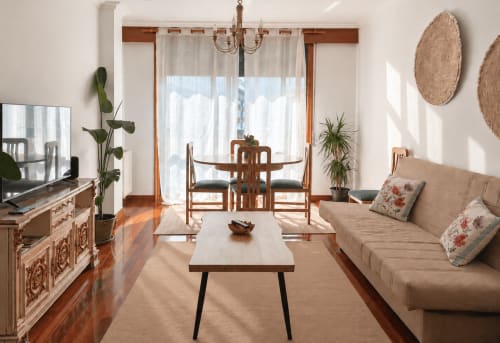 Luminoso salón del apartamento Baiona con muebles de madera, sofá beis, zona de comedor y vistas a la ciudad desde las puertas acristaladas