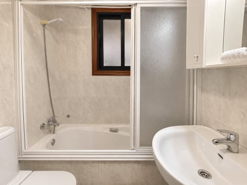 Baño moderno en apartamento Holibai, Baiona con bañera, ducha independiente y lavabo redondo con espejo