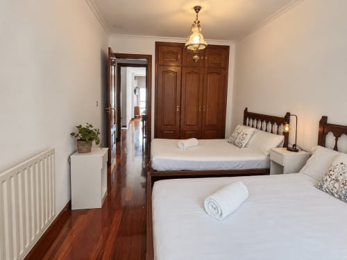 Acogedora habitación doble en apartamento Amieiro, Baiona, con camas de madera, ropa blanca y suelos de madera