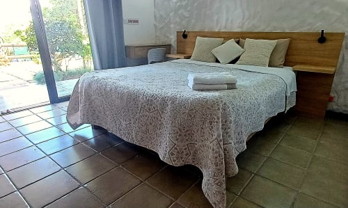 Modern apartment bedroom at Joubarbe Résidence in Moka with queen bed, wooden headboard, patterned bedding, and mountain