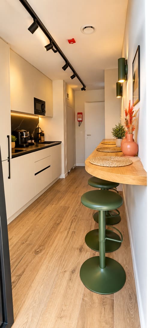 Cozinha e sala de jantar modernas da House Park B&B em Esposende com móveis brancos, bancada preta e bancos verdes