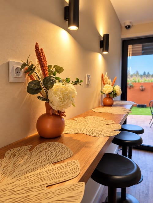 Área de refeições moderna da House Park B&B em Esposende com mesa de madeira, bancos altos, vasos de terracota com flores brancas e