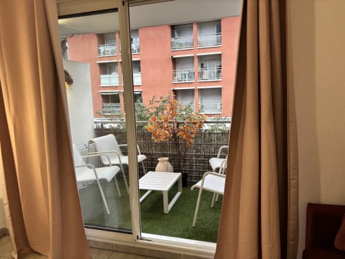 Prostor za sjedenje na balkonu s bijelim stolicama s pogledom na ružičasto građevinu u centru Aix-en-Provence