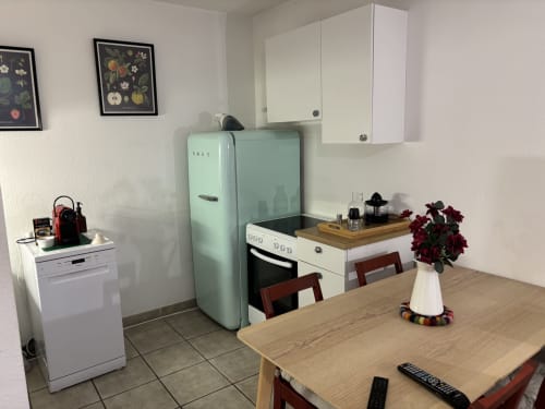 Cuisine moderne dans un appartement d'Aix-en-Provence avec réfrigérateur menthe, table à manger et décor floral