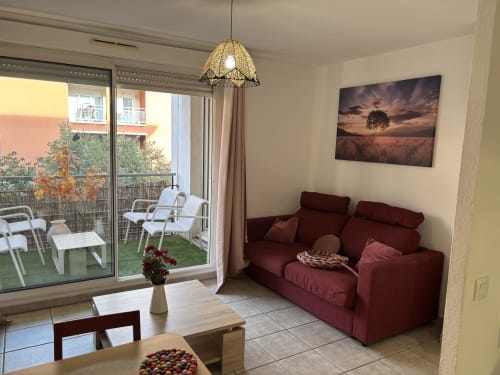 Appartement moderne à Aix-en-Provence avec canapé bordeaux, suspension, balcon vue ville et œuvres nature.