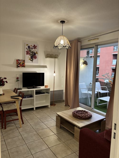 Salon moderne à Aix-en-Provence avec TV, luminaires suspendus et accès au balcon avec vue sur la ville
