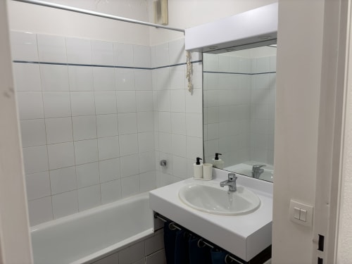 Salle de bain moderne à Aix-en-Provence avec carrelage blanc, lavabo rond, miroir et baignoire avec douche