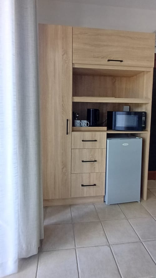 Studio kitchenette at Joubarbe Résidence in Moka with wooden cabinets, microwave, and compact refrigerator