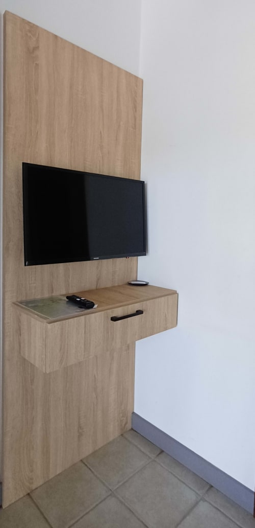 Modern wooden TV wall unit in Le Studio apartment at Joubarbe Résidence, Moka with mounted flat-screen and storage shelf