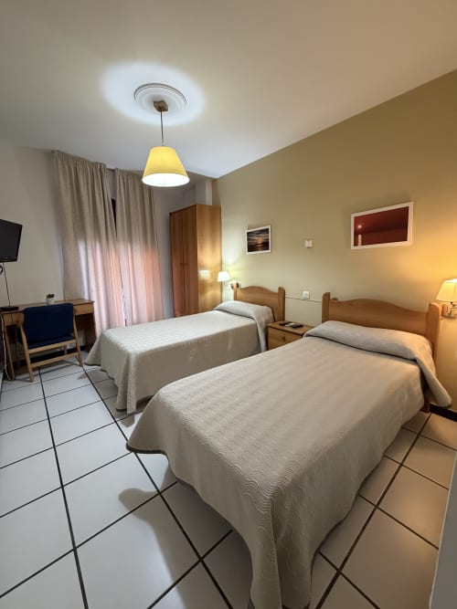Habitación con cama individual en Hotel JM El Emigrante de Villanueva de la Serena con iluminación cálida y comodidades modernas