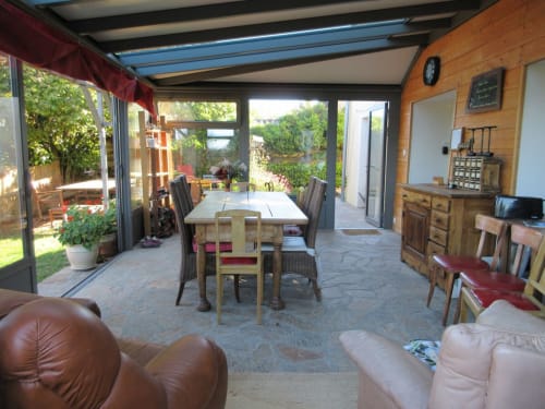 Spacieux salon-véranda de La Ferme Buissonnière avec table à manger et vue sur le jardin