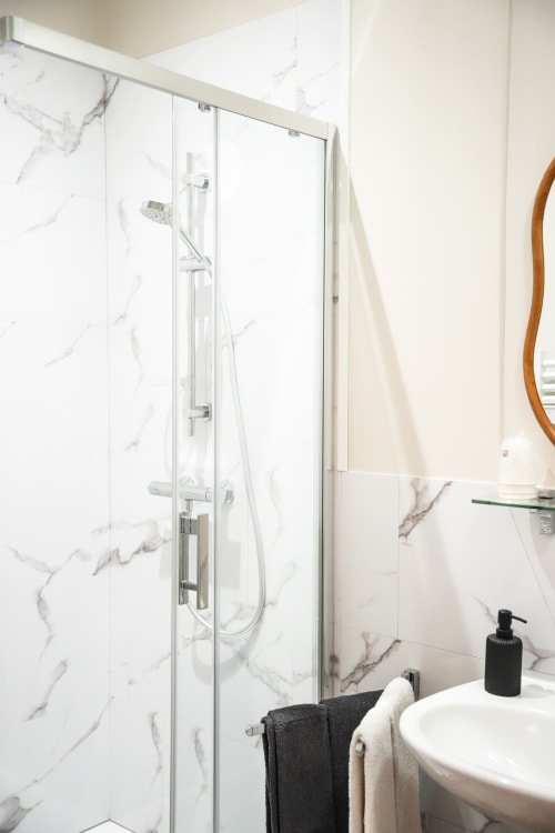 Baño moderno con ducha efecto mármol en el hotel Le Saint Laurans en Aurignac, Francia