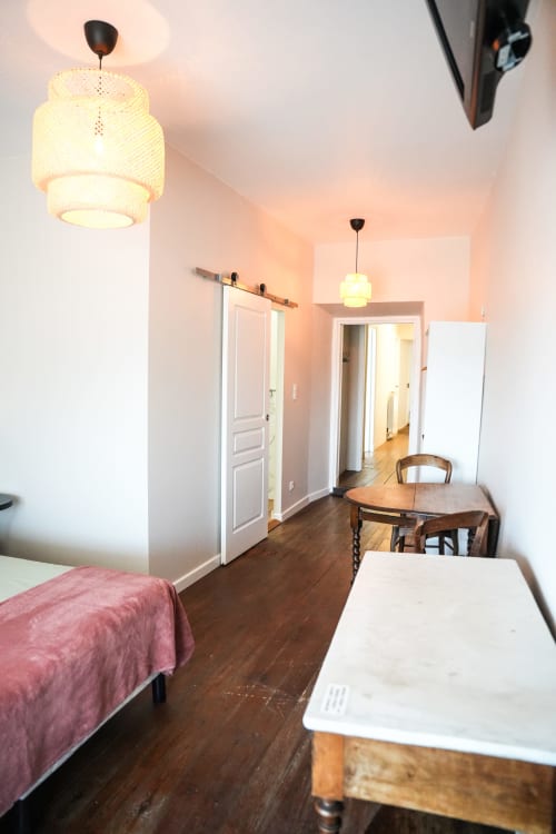 Habitación A del hotel Le Saint Laurans en Aurignac con cama, mesa de comedor, iluminación colgante y puerta abierta