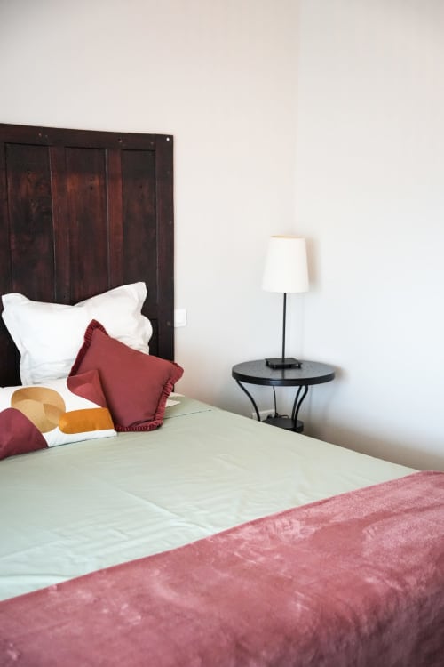 Dormitorio elegante en el hotel Le Saint Laurans en Aurignac con cabecero de madera oscura, almohadas granate y lámpara de mesita de noche