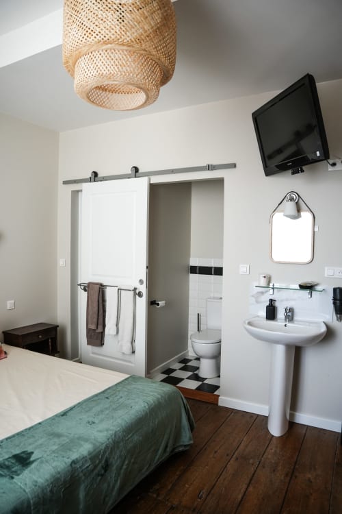 Chambre B at Le Saint Laurans in Aurignac features a bed, en-suite bathroom with pedestal sink, mirror, TV, and woven ceiling