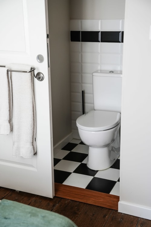Modern bathroom in Le Saint Laurans hotel room with black and white checkered floor, white toilet, and shower enclosure