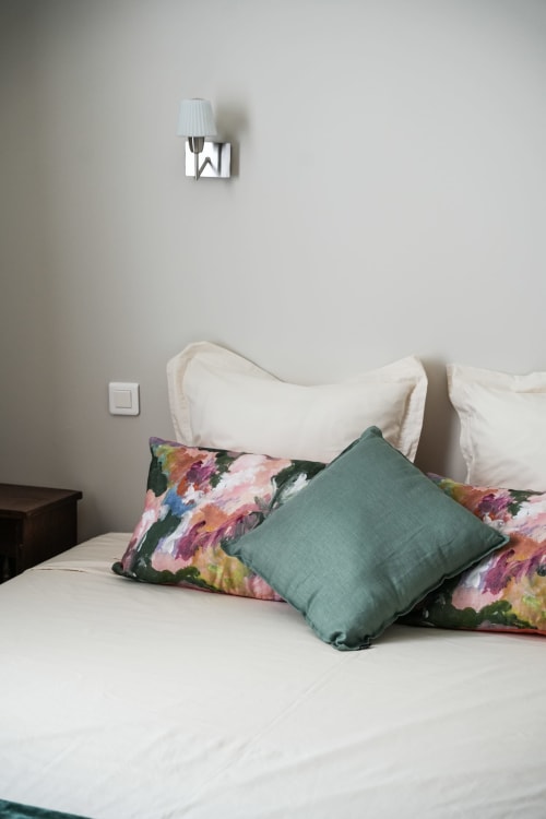 Cozy bedroom at Le Saint Laurans hotel in Aurignac with colorful floral pillows and white bedding