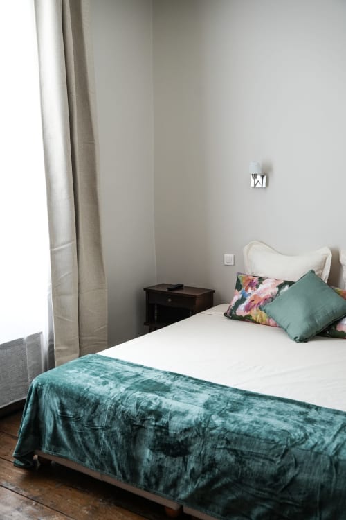 Cozy bedroom at Le Saint Laurans hotel in Aurignac with white bed, teal bedding, and natural light from window