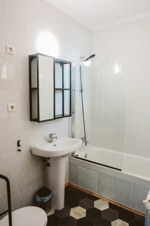 Modern bathroom in Balcó del Priorat hotel with pedestal sink, shower enclosure, and black hexagonal floor tiles