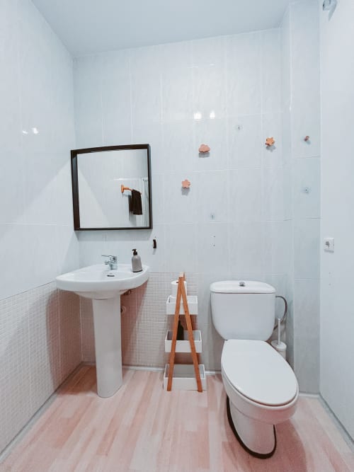 Modern bathroom at Balcó del Priorat hotel in Tarragona with pedestal sink, toilet, and wooden ladder decor on pink wood