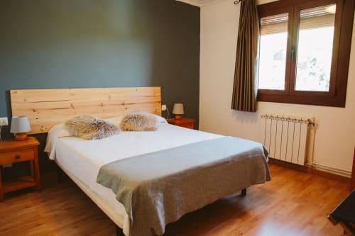 Habitación moderna en el hotel Balcó del Priorat con cama de madera, ropa de cama blanca y vistas a las montañas en Tarragona