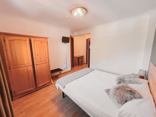 Moderno dormitorio doble en el hotel Balcó del Priorat de Tarragona con muebles de madera, ropa de cama blanca, TV y vistas a la montaña