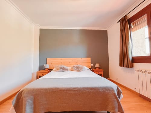 Luminosa habitación doble en el hotel Balcó del Priorat de Tarragona con cama de madera, vistas a la montaña y comodidades modernas