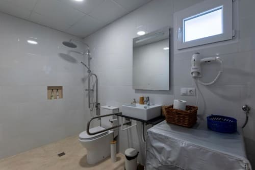 Baño moderno en Cal Xot con azulejos blancos, ducha, lavamanos, espejo y ventana en Poble Nou del Delta
