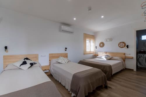 Habitación cuádruple luminosa en Cal Xot con cuatro camas de madera, paredes blancas y vistas al patio en Poble Nou del Delta