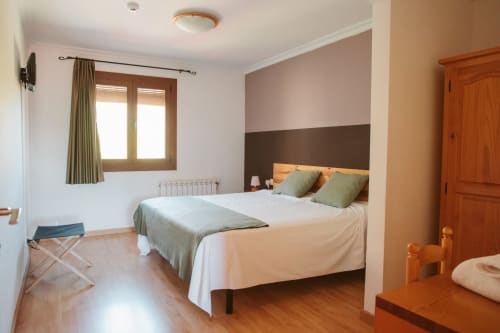 Bright double bedroom at Balcó del Priorat hotel in Tarragona with wooden furniture, two-tone accent wall, and mountain views