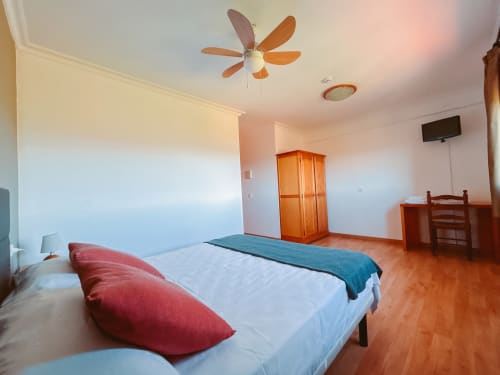 Amplia habitación doble en el hotel Balcó del Priorat de Tarragona con ventilador de techo de madera, suelo de barro y vistas a la montaña