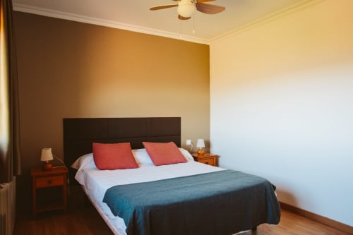 Habitación doble en el hotel Balcó del Priorat en Tarragona con cabecero oscuro, almohadas rojas y vistas a la montaña