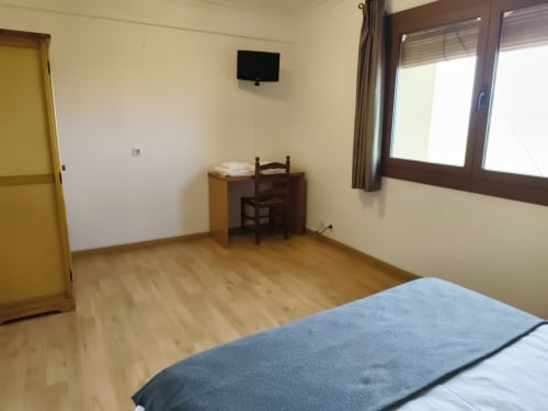 Amplia habitación doble del hotel Balcó del Priorat en Tarragona con suelos de madera, escritorio, TV y vistas a las montañas