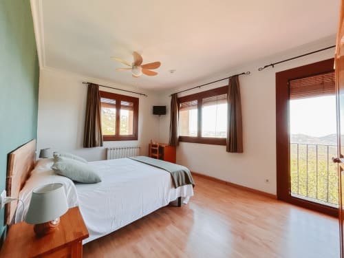 Spacious corner bedroom at Balcó del Priorat with mountain views, wooden flooring, and balcony access in Tarragona