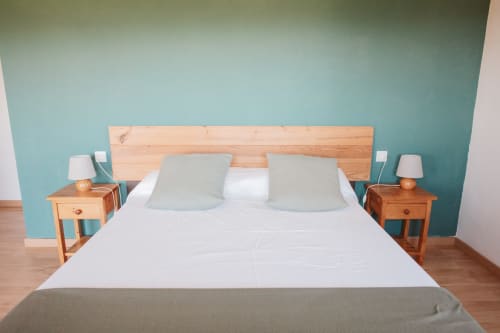 Modern bedroom at Balcó del Priorat in Tarragona with turquoise accent wall, wooden bed, and side tables with lamps