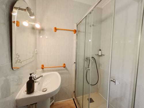 Baño moderno en hotel Balcó del Priorat con azulejos blancos, lavabo redondo, espejo con luces de tocador y ducha de cristal