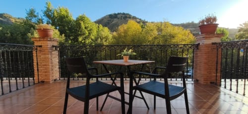 Terraza con vistas a la montaña en Hospedería Puerta a los Cahorros con asientos, mesa y paisaje del valle en Monachil